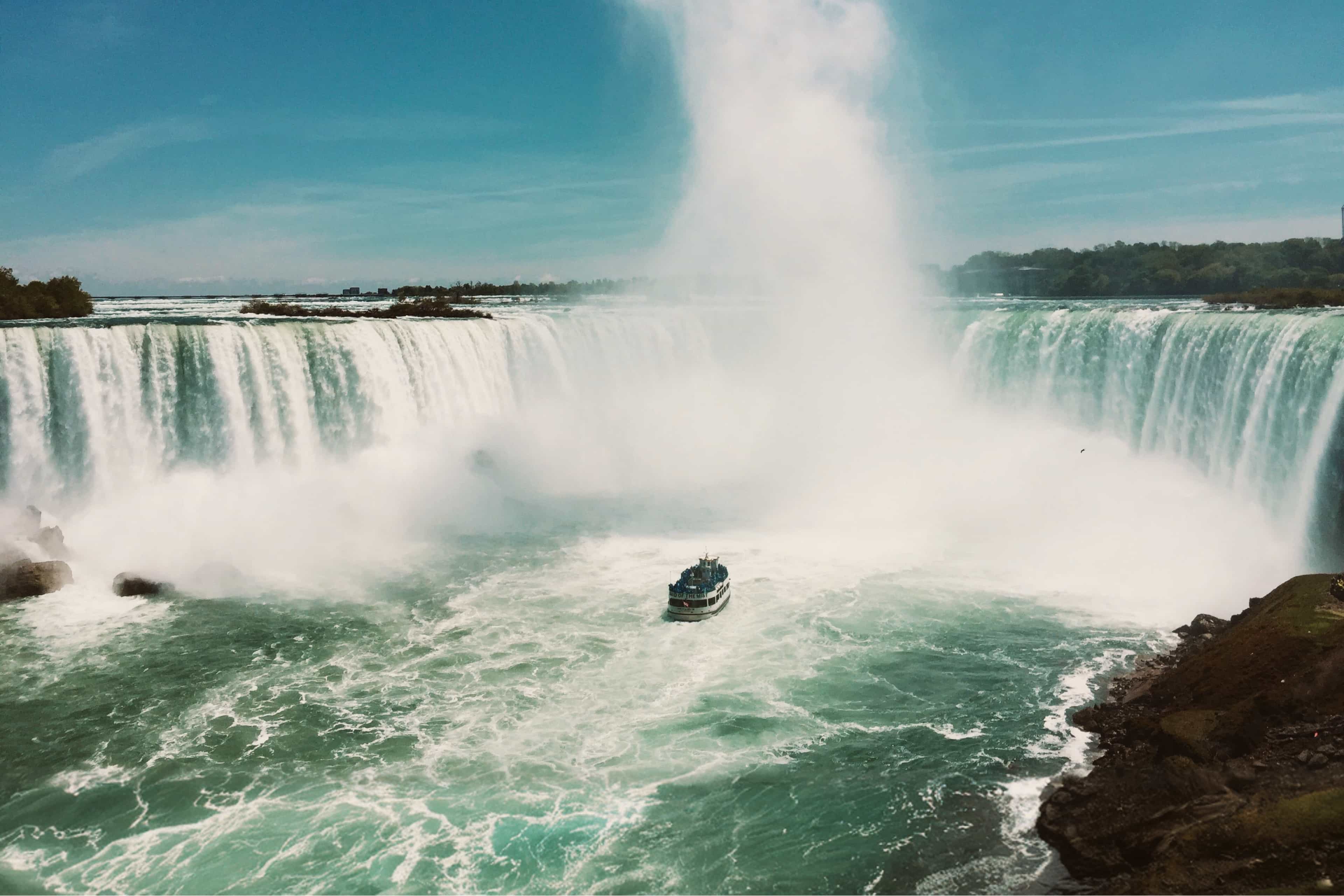 Tour boat approaching the base of Niagara Falls beneath rising mist, Canada.