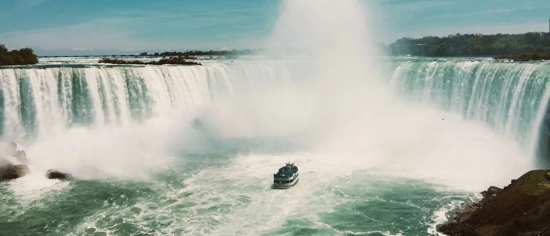 Tour boat approaching the base of Niagara Falls beneath rising mist, Canada.