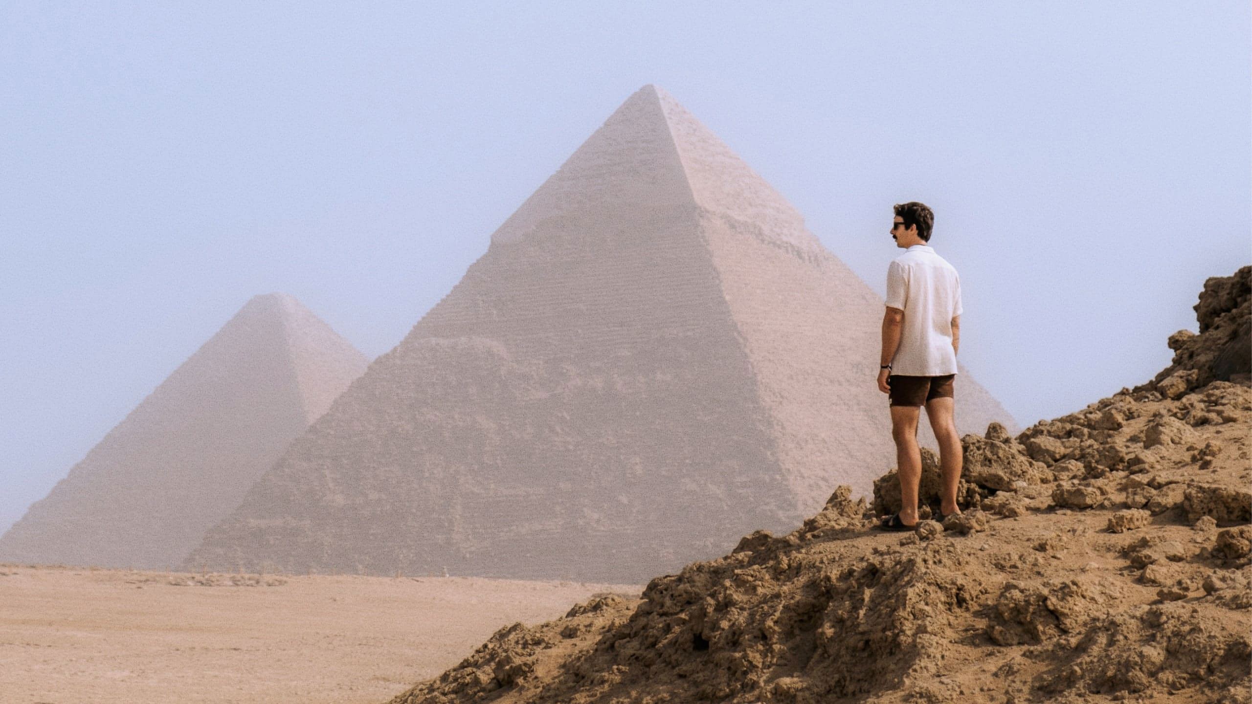 A Contiki traveller stands in the desert overlooking the Pyramids of Giza, taking in one of Egypt's most iconic ancient landmarks - Egypt Explorer Tour