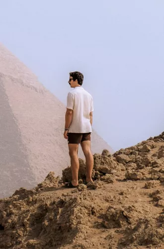 A Contiki traveller stands in the desert overlooking the Pyramids of Giza, taking in one of Egypt's most iconic ancient landmarks - Egypt Explorer Tour
