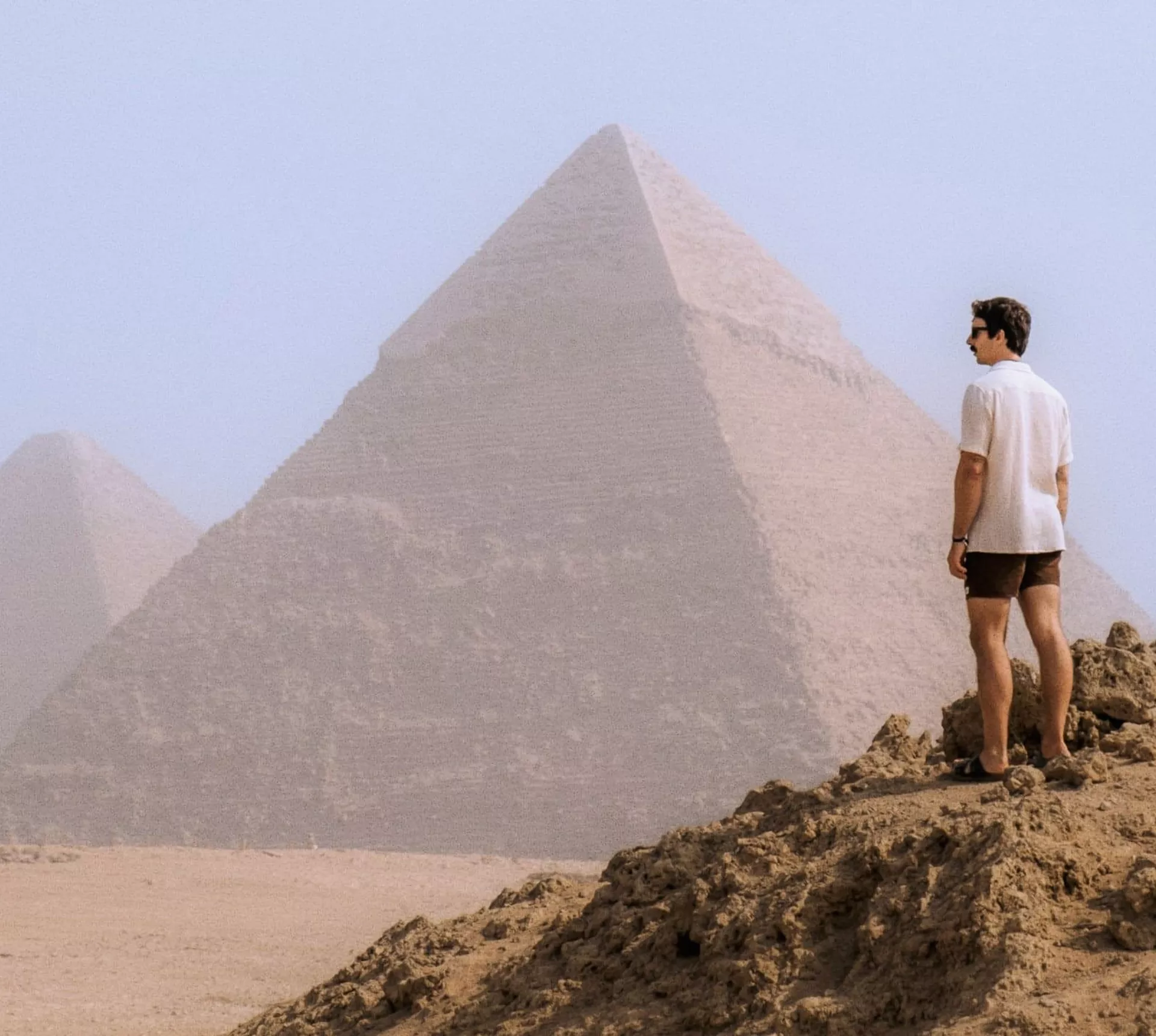 A Contiki traveller stands in the desert overlooking the Pyramids of Giza, taking in one of Egypt's most iconic ancient landmarks - Egypt Explorer Tour