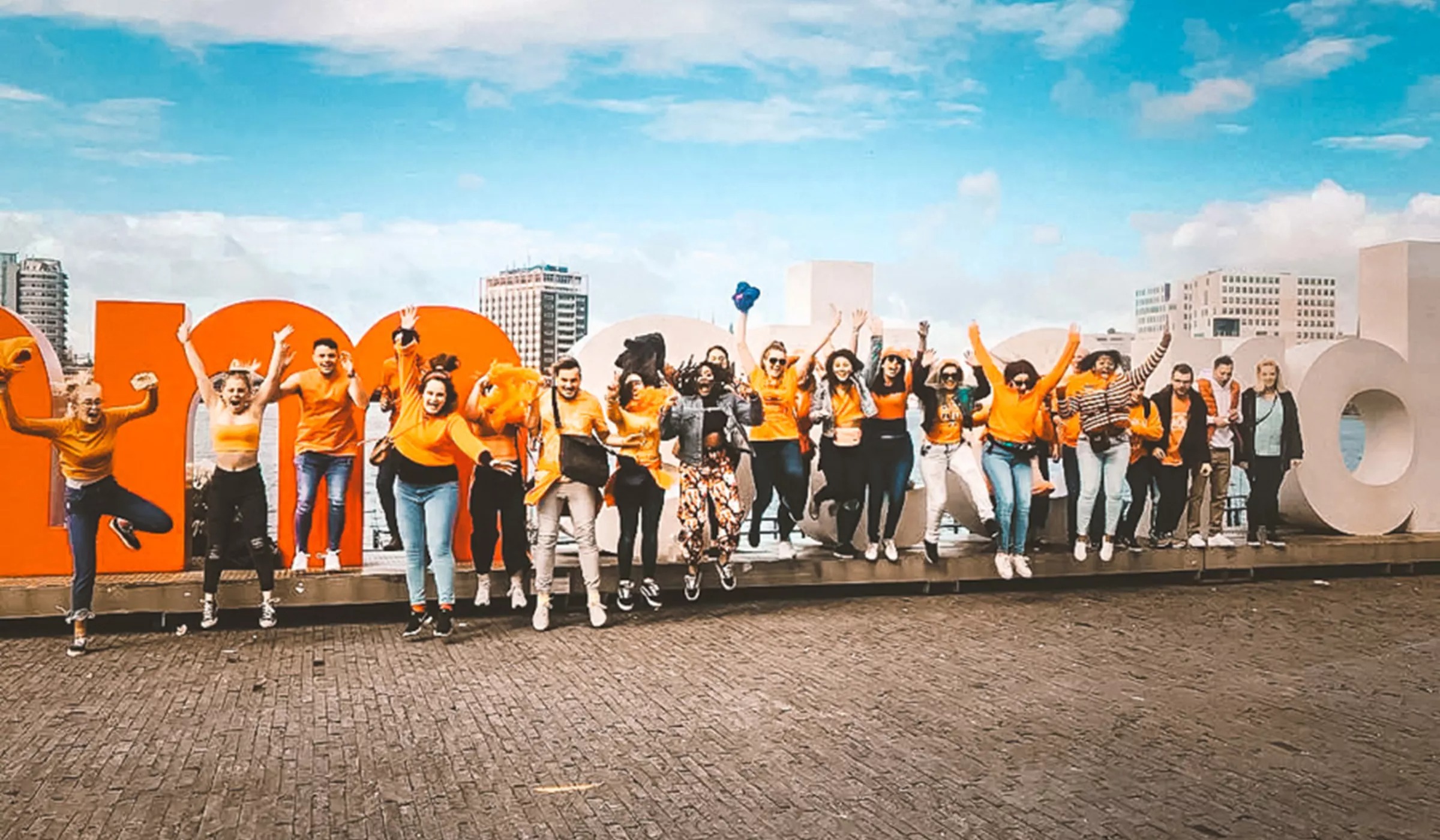 People jumping on the Amsterdam sign at the back.