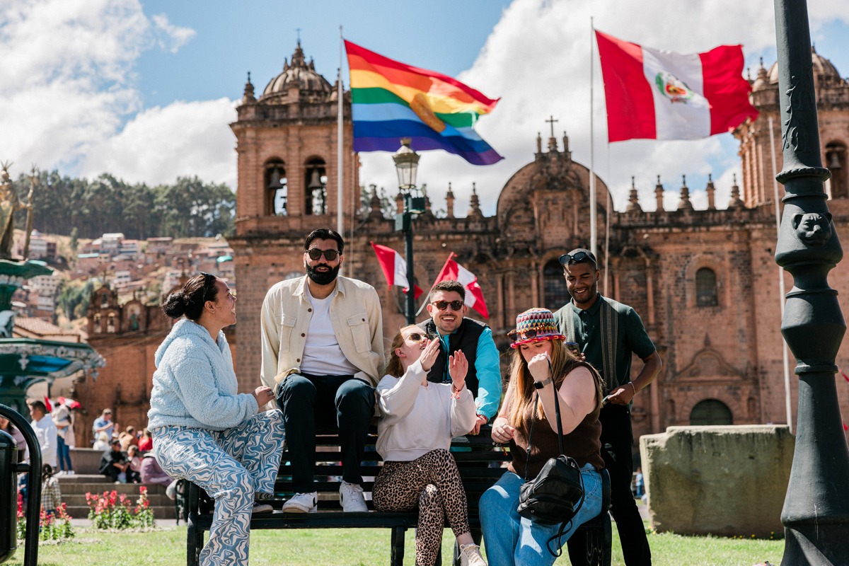 A group of young people smiling and talking while sitting on a bench in Peru.