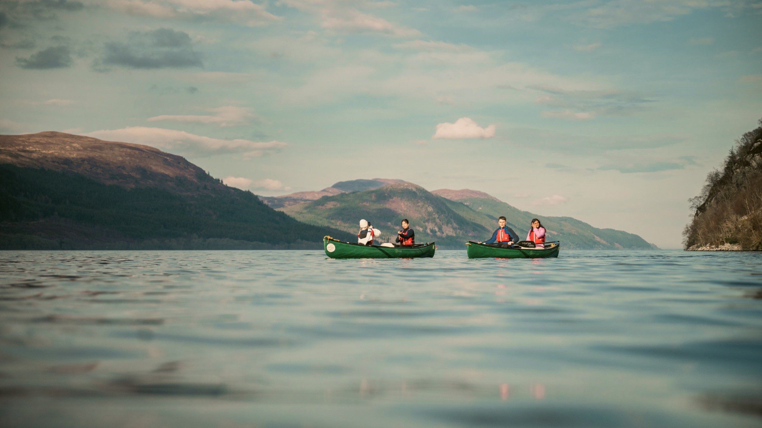 Contiki travellers canoeing across Loch Ness, surrounded by the Scottish Highlands, enjoying an unforgettable outdoor adventure on the Scotland in a Week 35 to 45 Tour