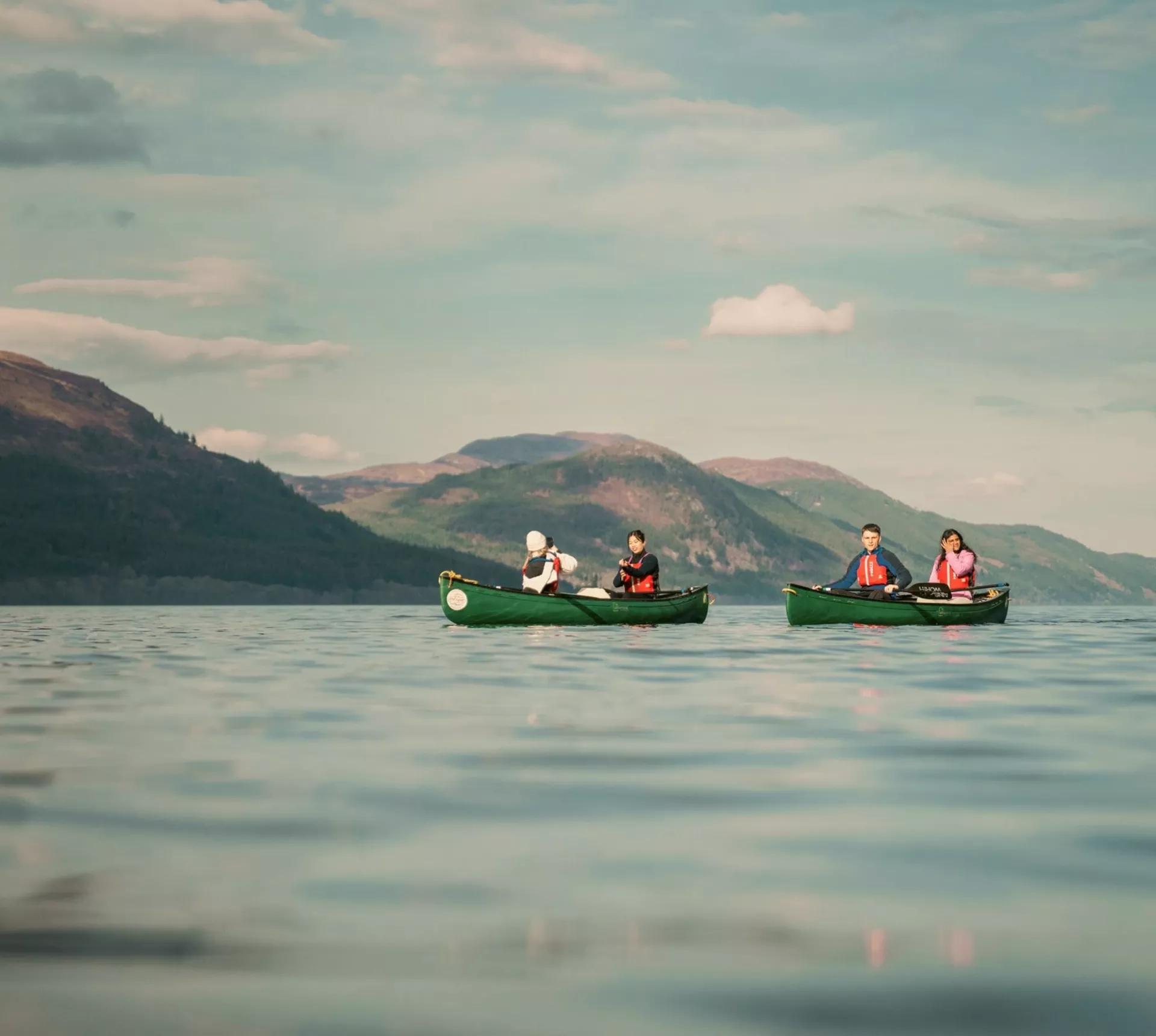 Contiki travellers canoeing across Loch Ness, surrounded by the Scottish Highlands, enjoying an unforgettable outdoor adventure on the Scotland in a Week 35 to 45 Tour