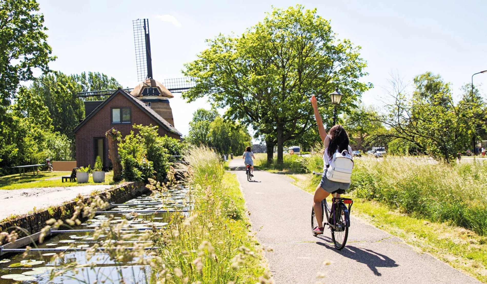 Biking ride next to a windmill on a sunny day.