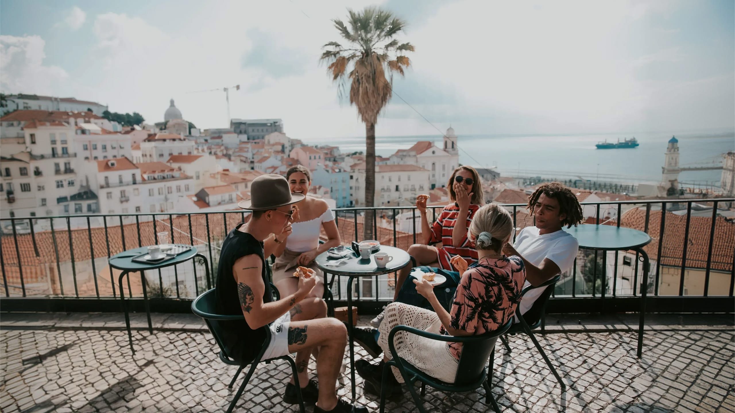 A group relaxing at a terrace café overlooking Lisbon on Contiki's Best of Portugal Tour