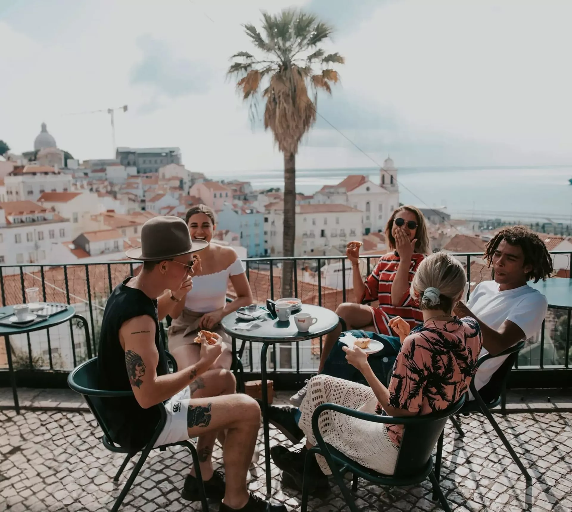 A group relaxing at a terrace café overlooking Lisbon on Contiki's Best of Portugal Tour