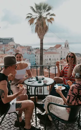 A group relaxing at a terrace café overlooking Lisbon on Contiki's Best of Portugal Tour