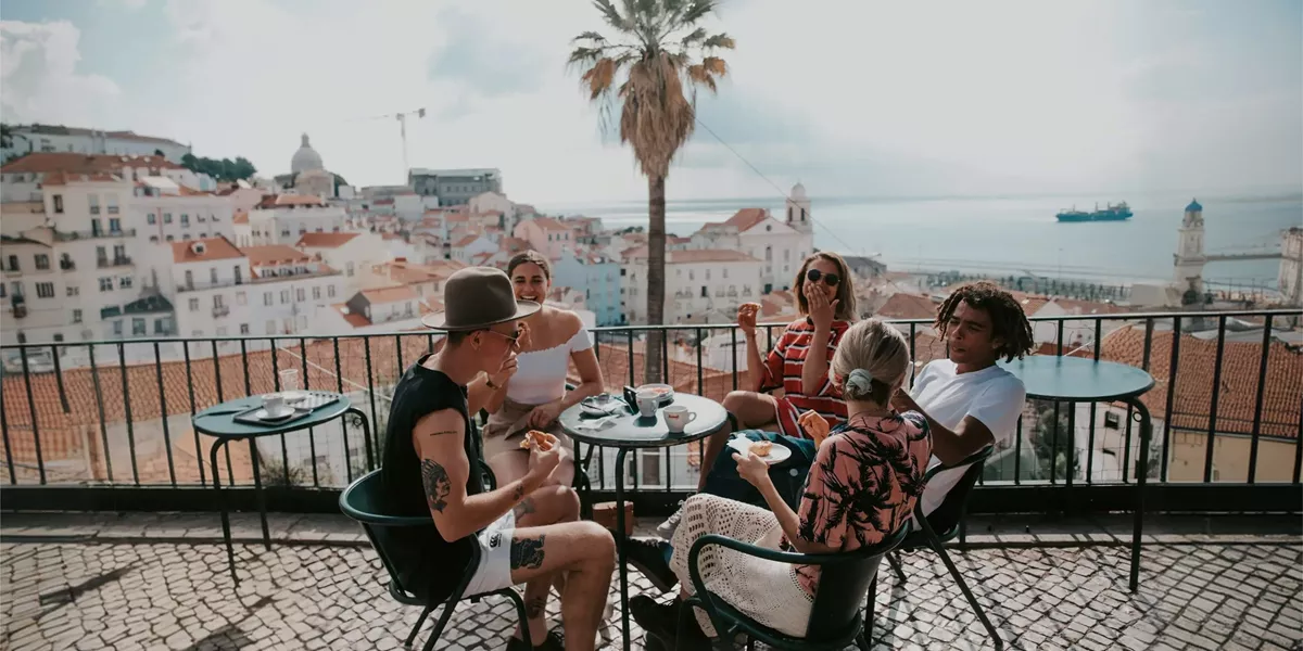 A group relaxing at a terrace café overlooking Lisbon on Contiki's Best of Portugal Tour