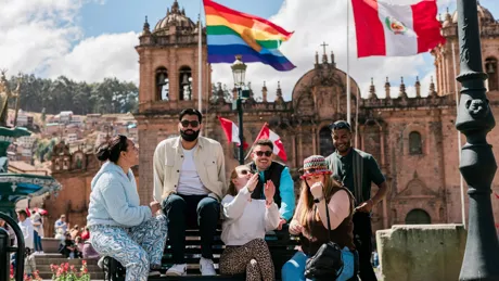 Group of young people smiling and talking while sitting on a bench