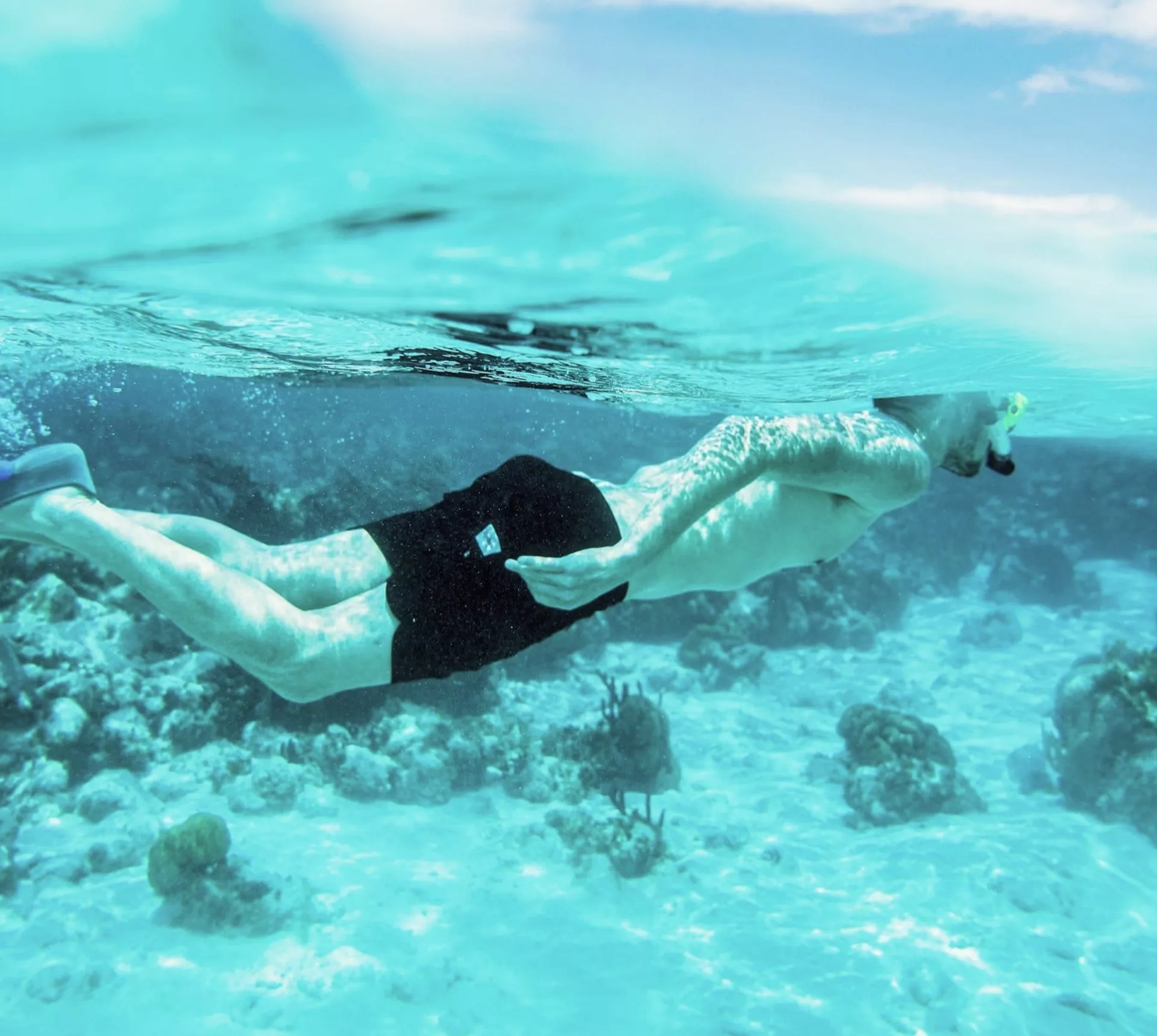 Snorkelling above colourful coral reefs, a Contiki traveller explores the Great Barrier Reef on the Whitsundays to Cairns Tour