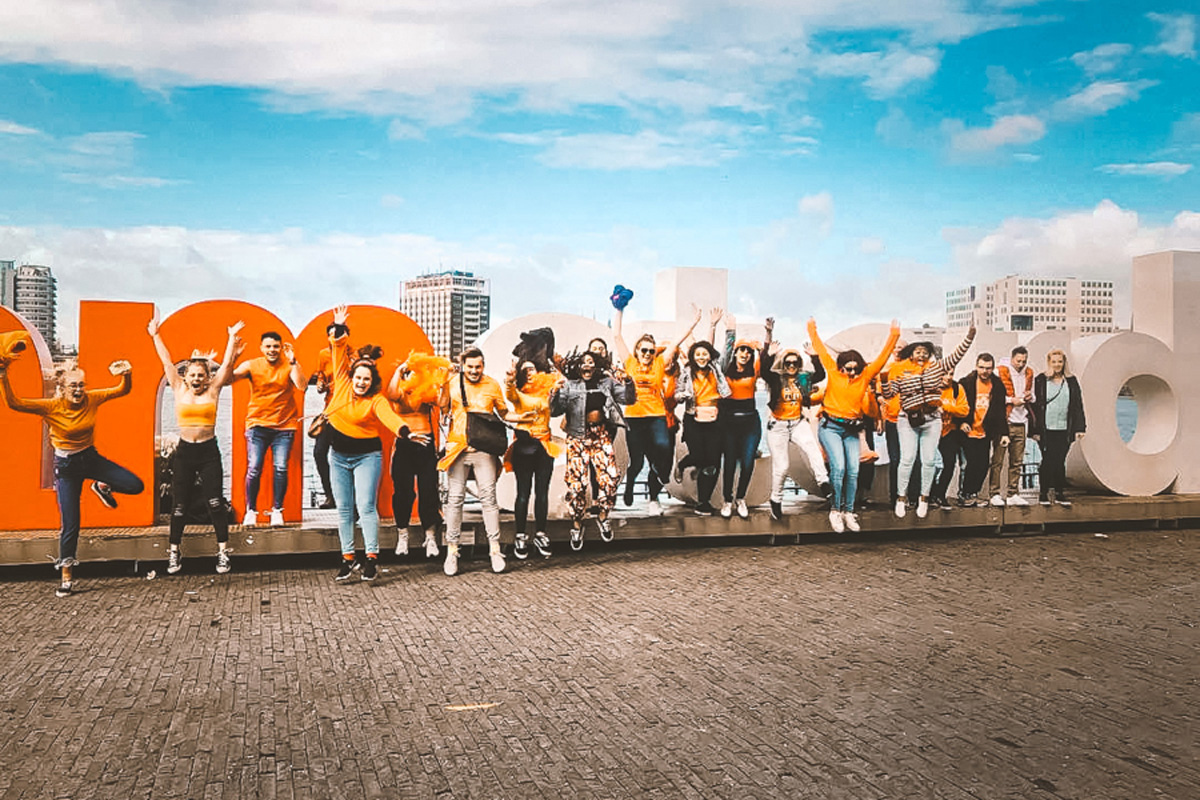 People Jumping Amsterdam Sign At The Back