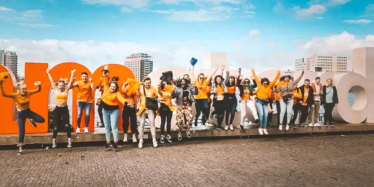 People Jumping Amsterdam Sign At The Back