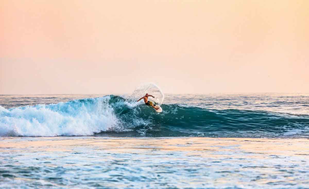 Surfer Riding A Wave At Sunset