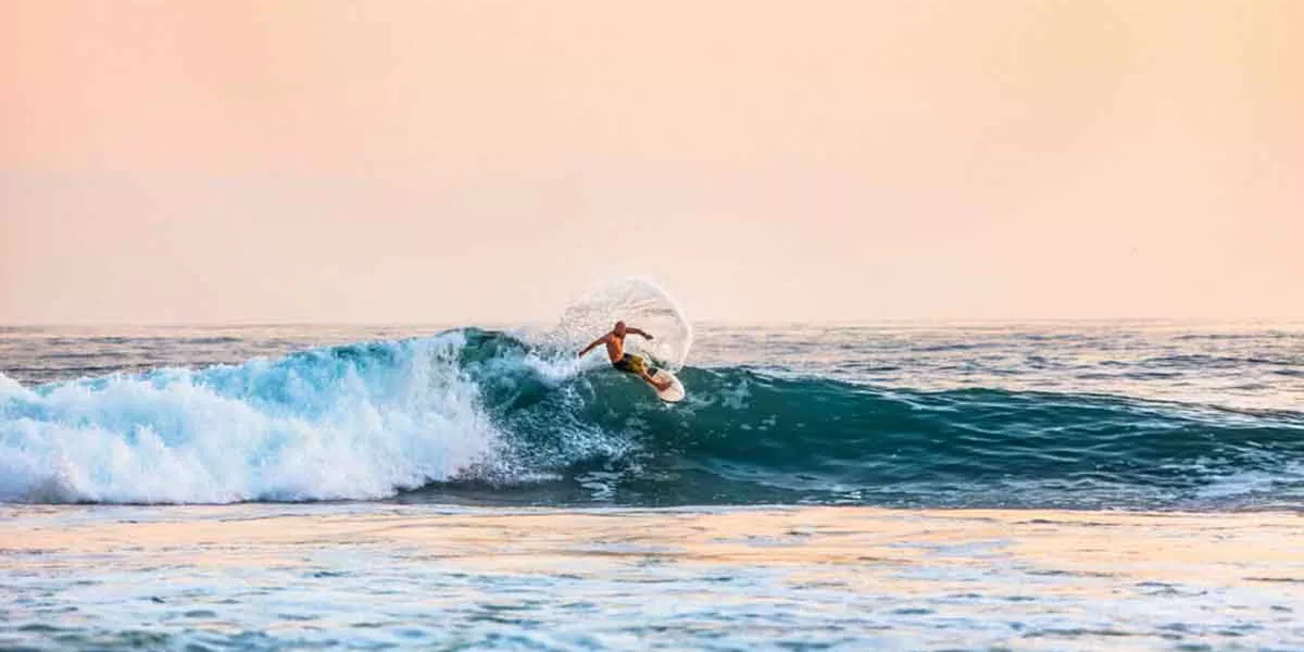 Surfer Riding A Wave At Sunset