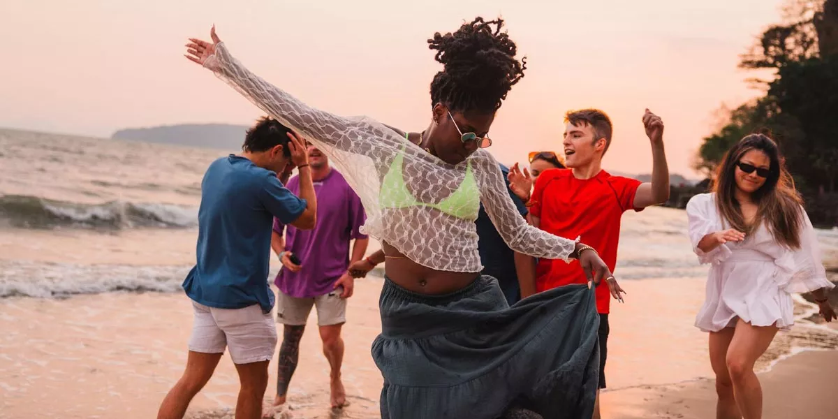 Friends dancing on the beach on a sunny day in Thailand.
