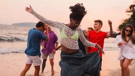 Friends dancing on the beach on a sunny day in Thailand.