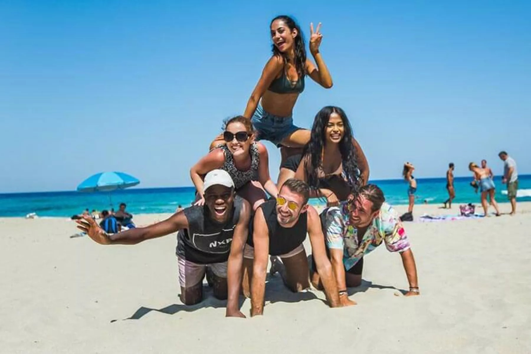 Travellers creating human pyramid on beach