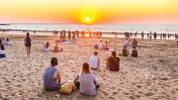 People resting on the beach during the sunset