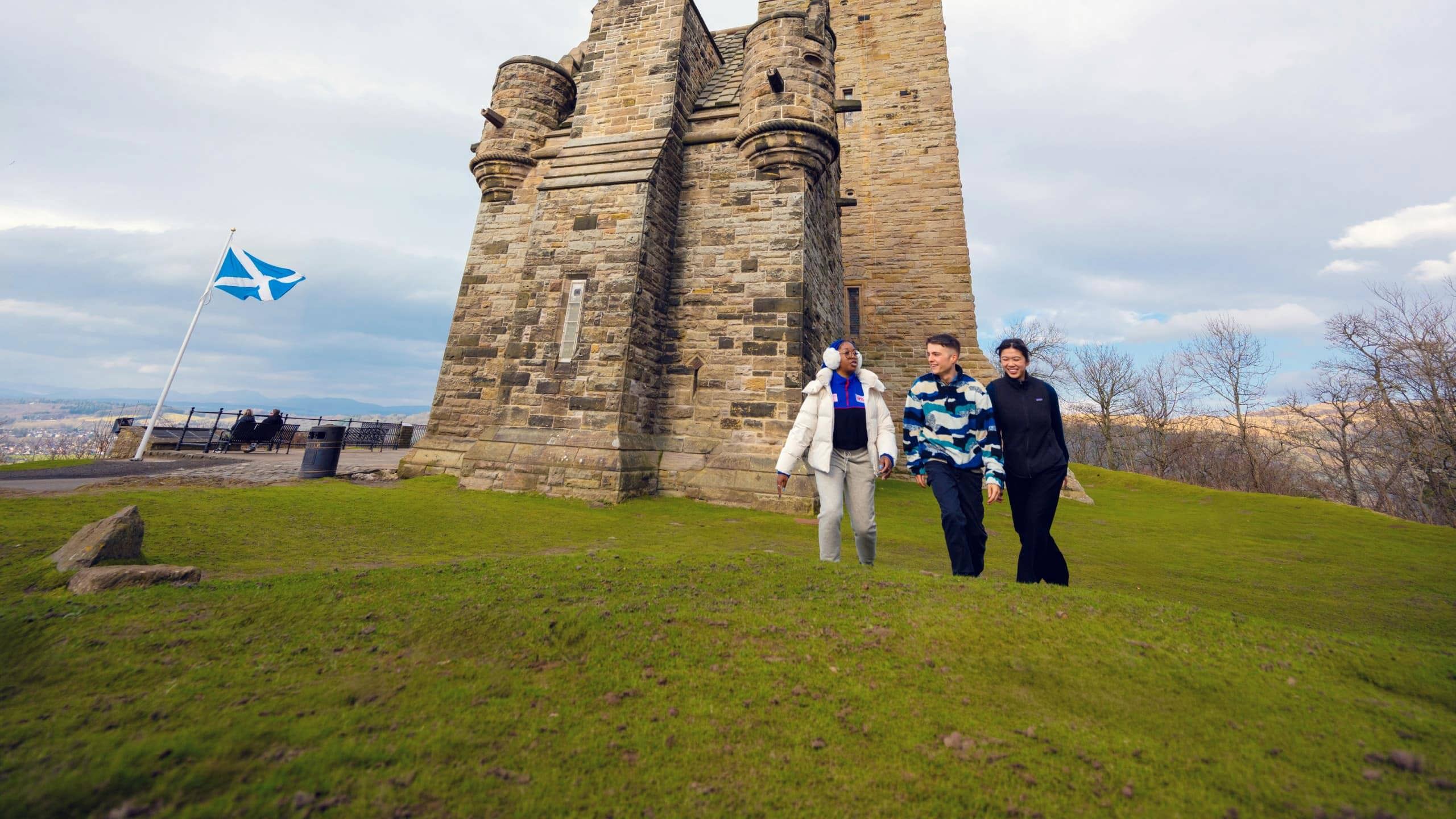 Travellers walk beside the National Wallace Monument in Stirling, Scotland, on the Contiki Best of Scotland & Ireland Tour