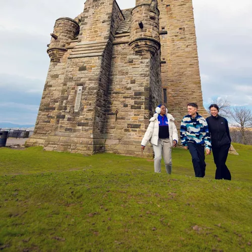 Travellers walk beside the National Wallace Monument in Stirling, Scotland, on the Contiki Best of Scotland & Ireland Tour