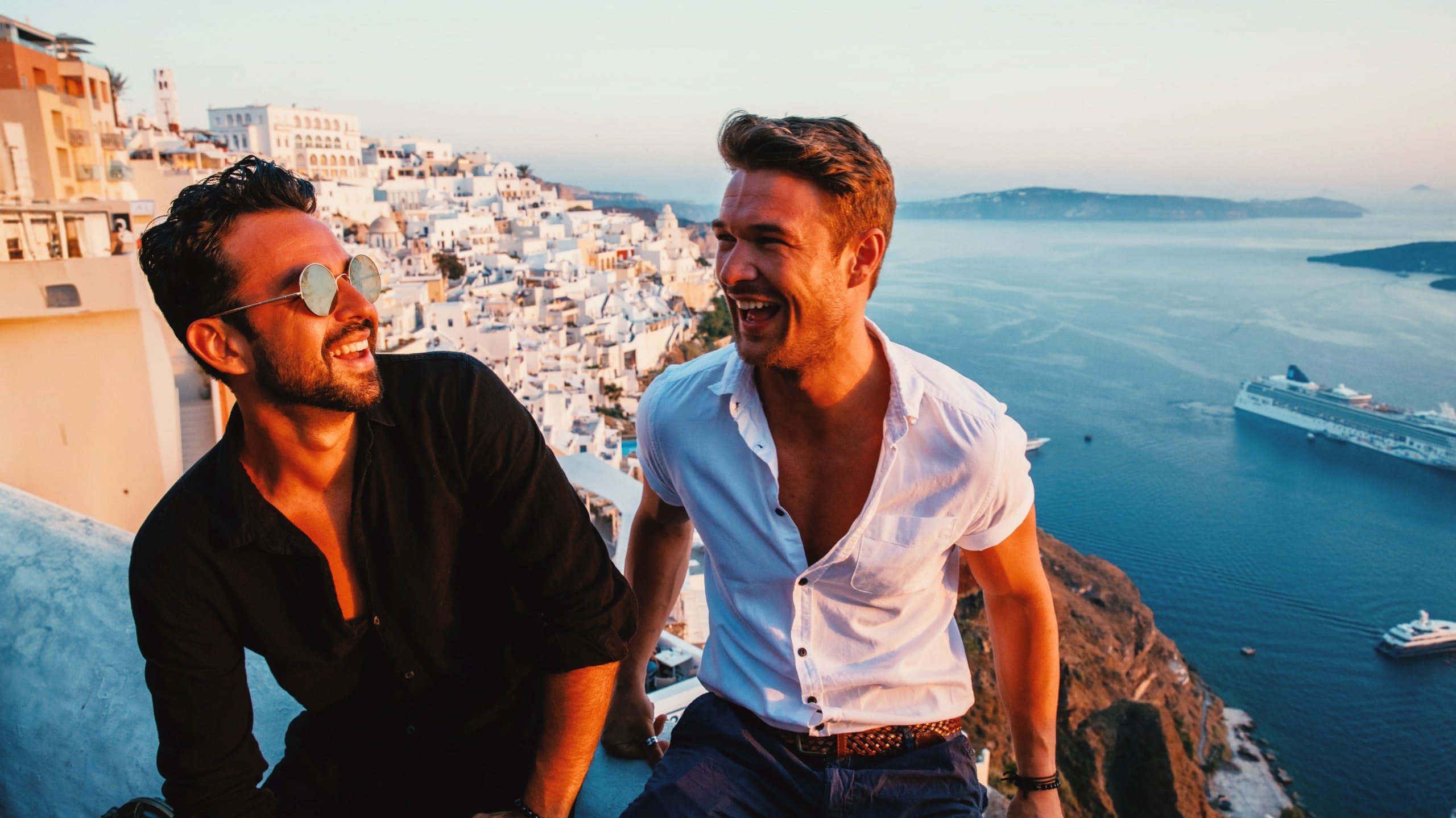 Friends enjoying sunset views over Santorini's whitewashed villages on Contiki's Athens to Santorini 35 to 45 Tour