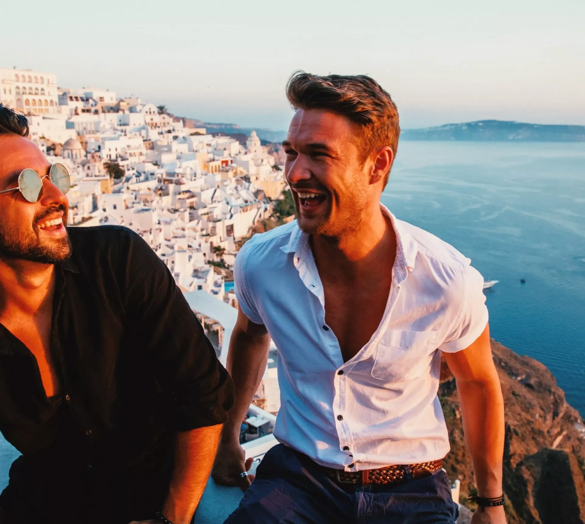 Friends enjoying sunset views over Santorini's whitewashed villages on Contiki's Athens to Santorini 35 to 45 Tour