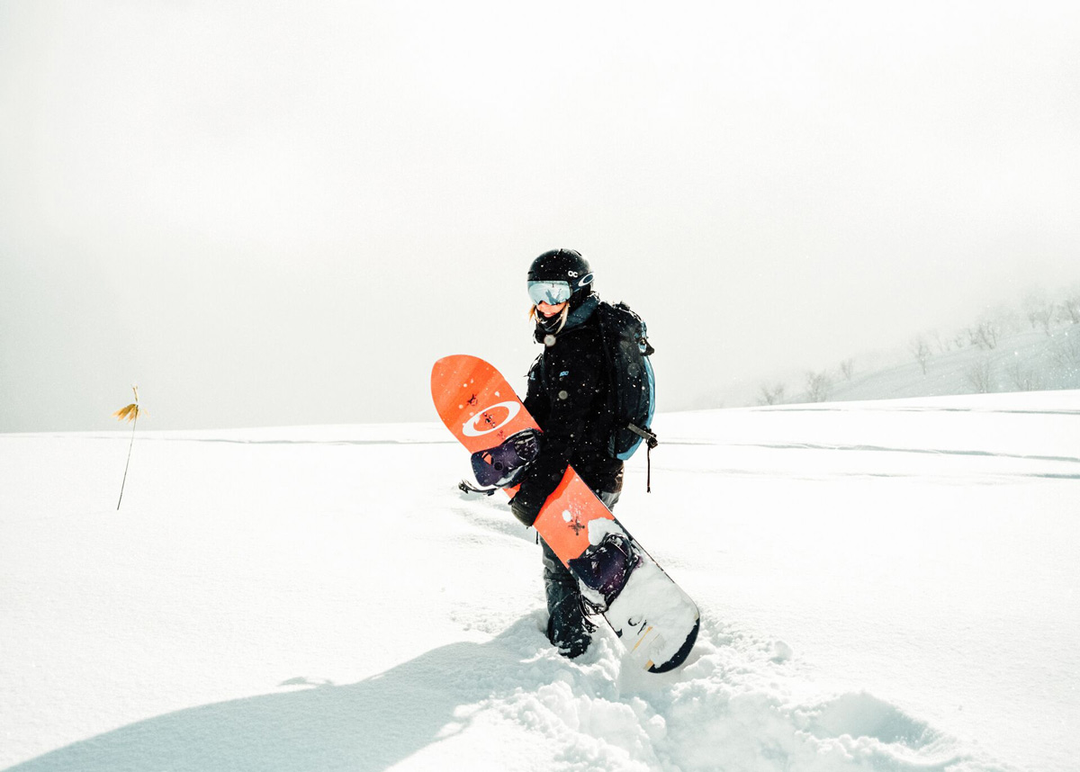 Woman Walking In Deep Snow Holding Snowboard