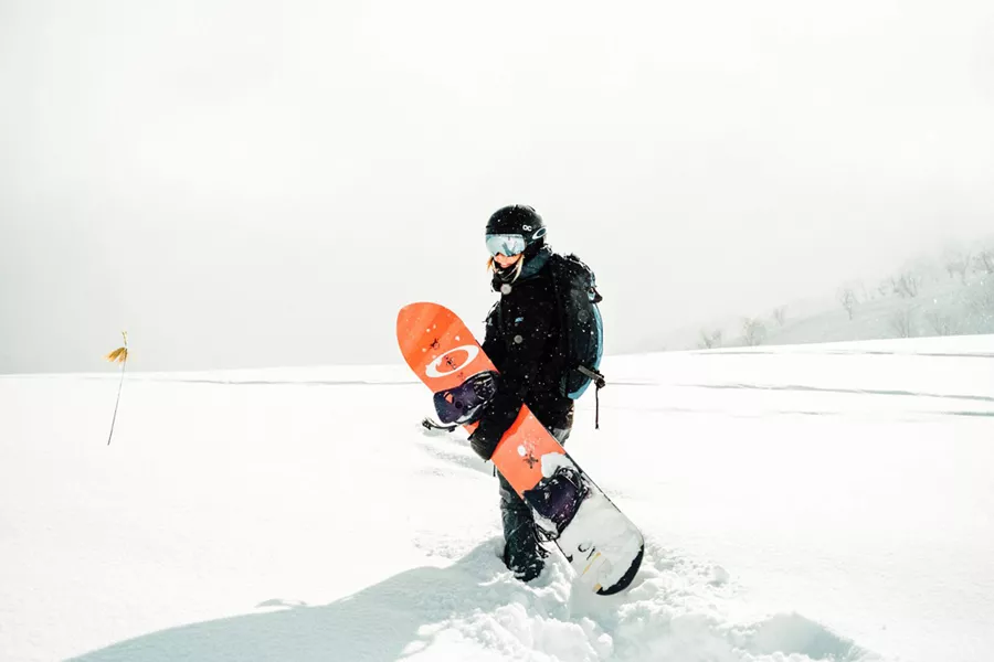 Woman Walking In Deep Snow Holding Snowboard