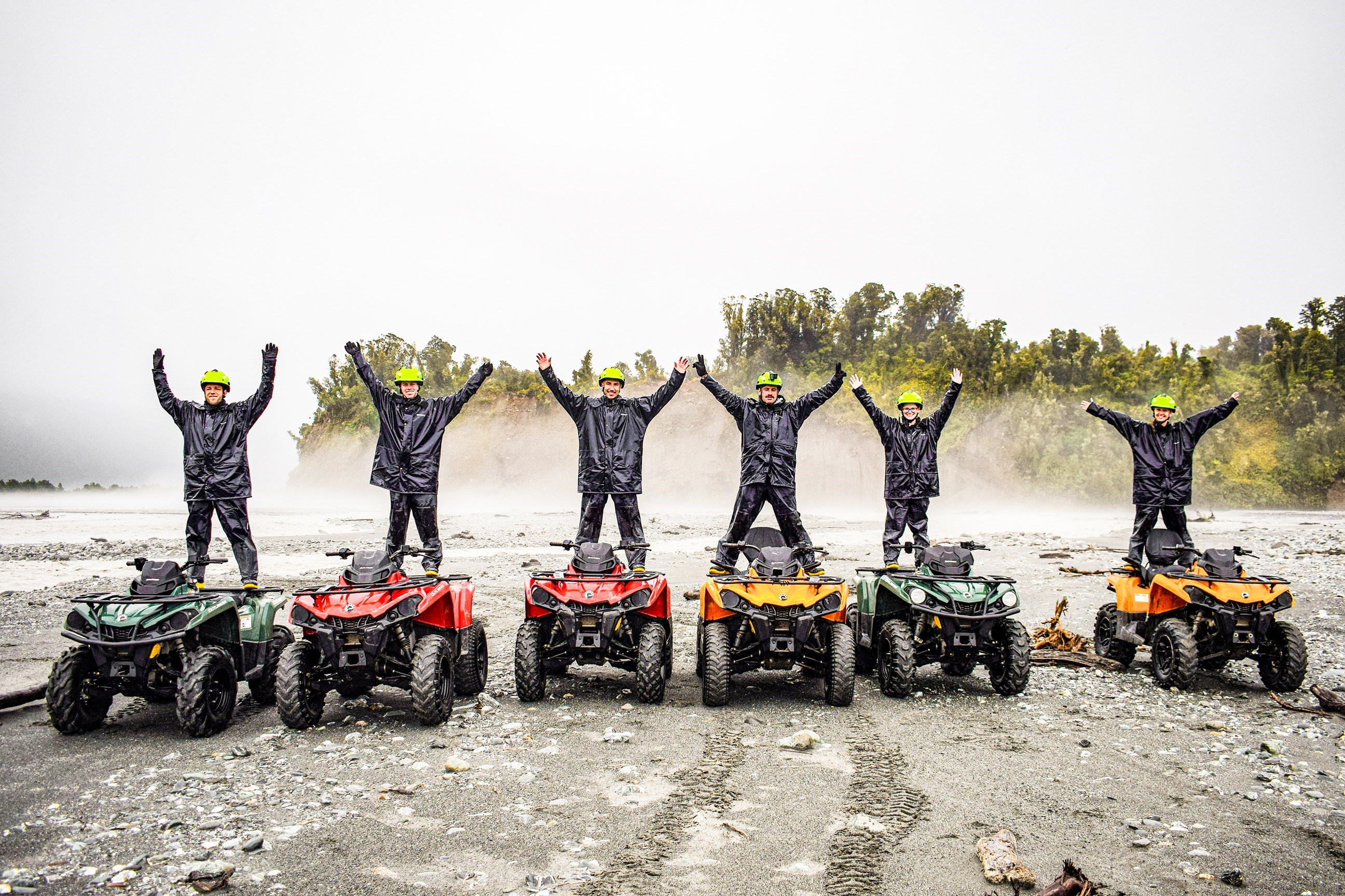 Travellers stood on top of quad bikes dressed in helmets and waterproofs, Franz Josef, New Zealand