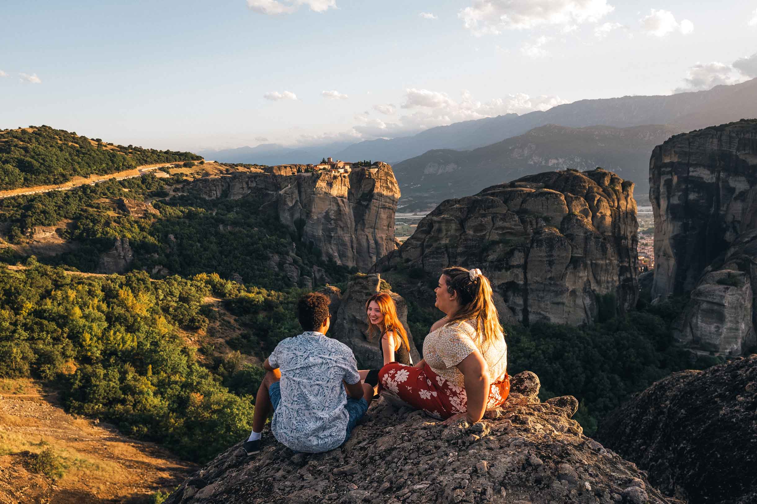 Trio Sitting On Mountains Enjoying The View In Greece