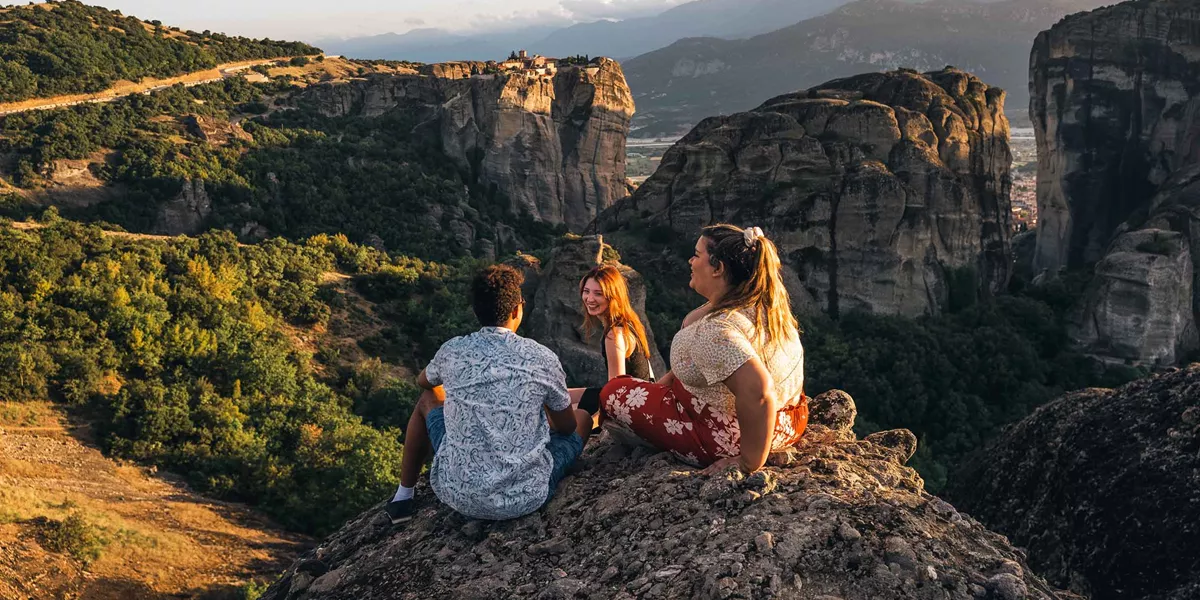 Trio Sitting On Mountains Enjoying The View In Greece