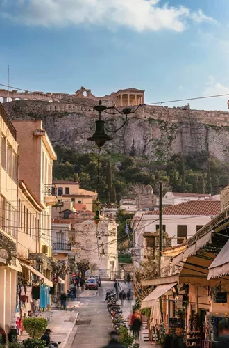 A lively street in Athens leads towards the Acropolis, with historic buildings, local shops and the ancient hilltop landmark in the distance - Greece: Ancient Wonders Tour