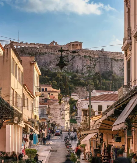 A lively street in Athens leads towards the Acropolis, with historic buildings, local shops and the ancient hilltop landmark in the distance - Greece: Ancient Wonders Tour