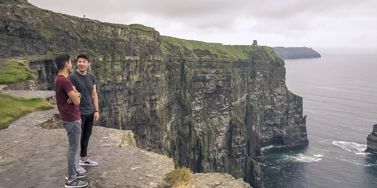 Two Friends Talking And Smiling At The Top Of A Clief