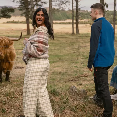 A group meeting a Highland cow in the Scottish Highlands - Contiki Scotland in a Week tour