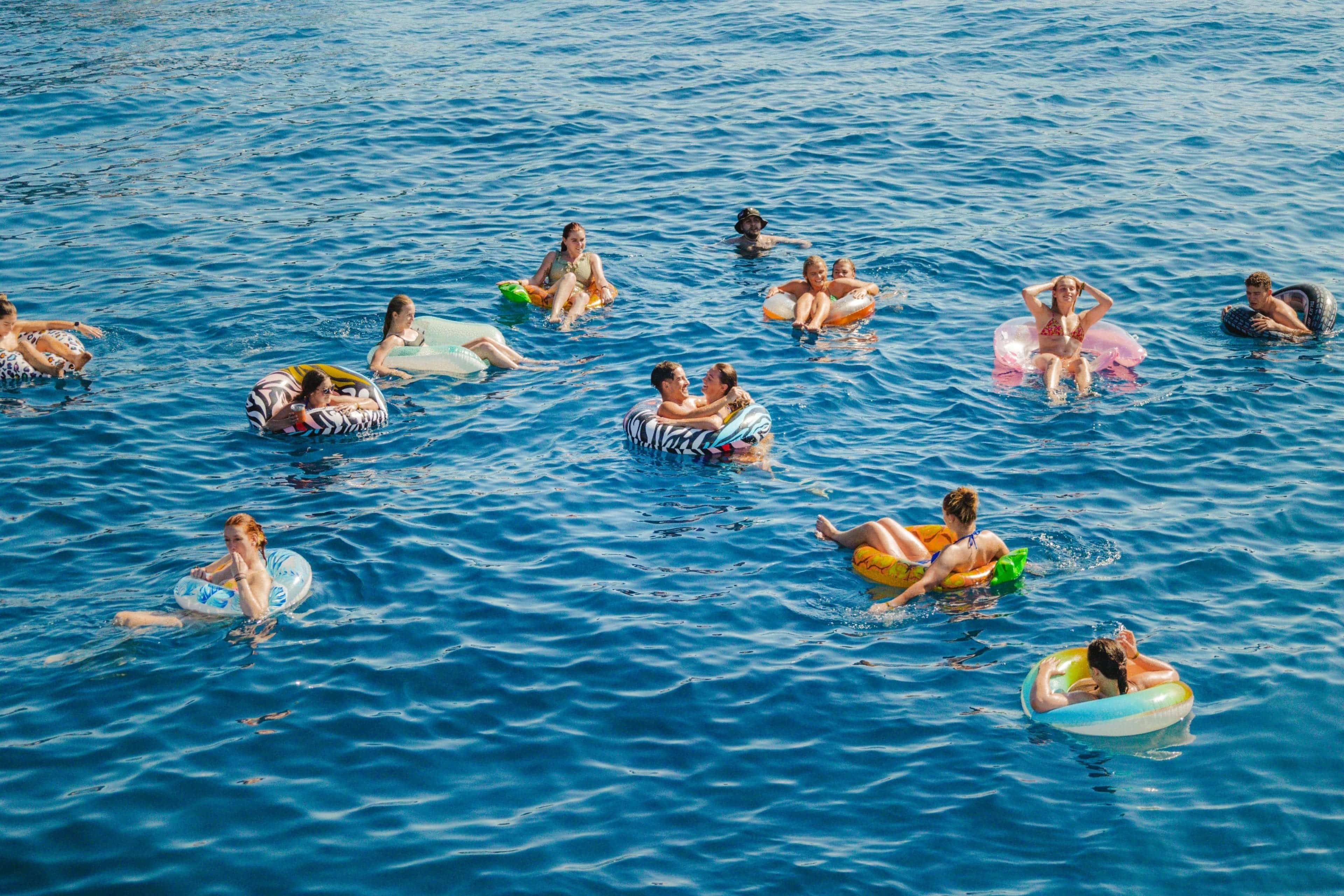Young travellers floating on inflatable rings in the crystal-clear Mediterranean Sea during a summer trip across Europe.