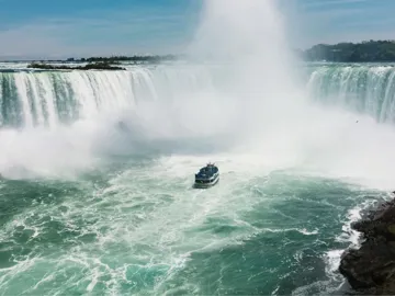 Boat sails through the mist beneath Niagara Falls on Contiki's Canada: Toronto, Niagara & Quebec Tour, experiencing one of Canada's most iconic natural wonders