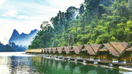 small-cabains-floating-on-water-trees-and-green-mountains-as-background.jpg