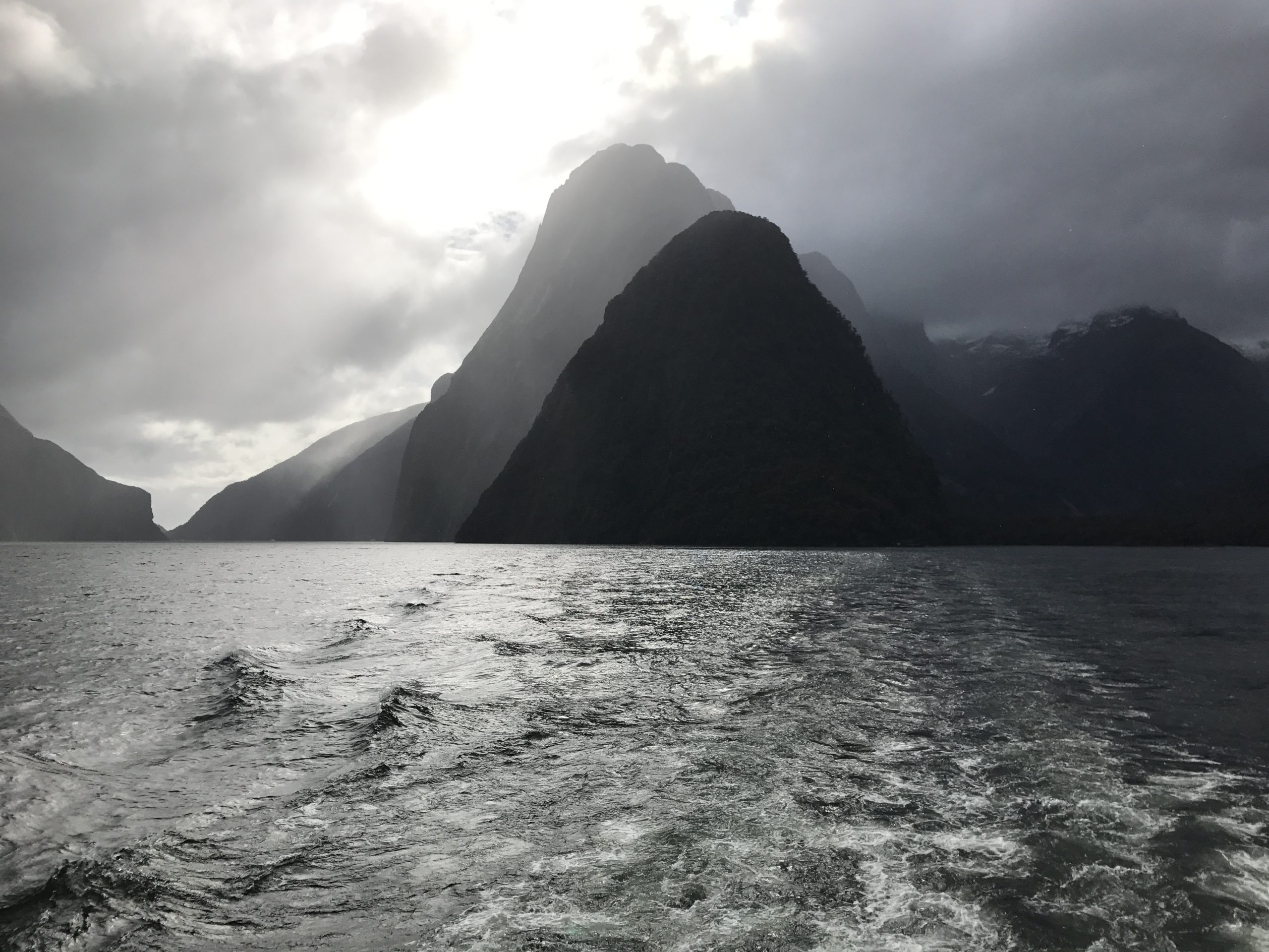 Sun shining on hills and sea in Queenstown, New Zealand.