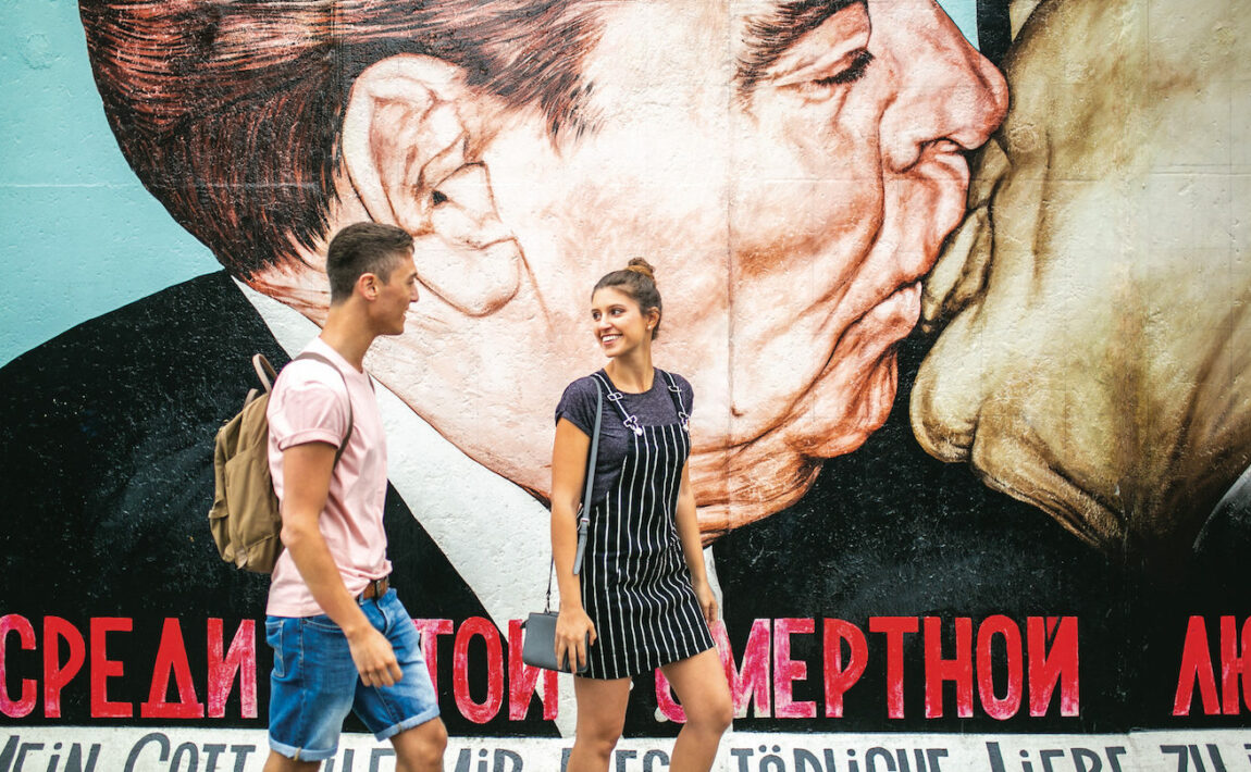 Two people in Berlin in front of political graffiti