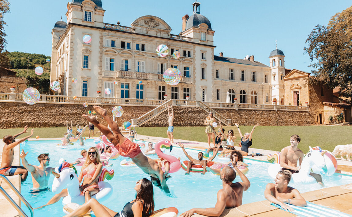 A group of people enjoying their gap year trips in a pool in front of a castle.