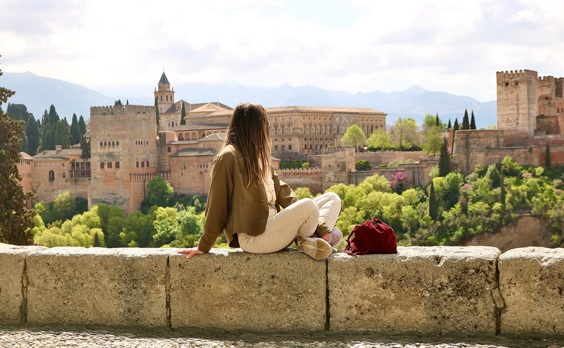 A woman is sitting on a wall in Granada.
