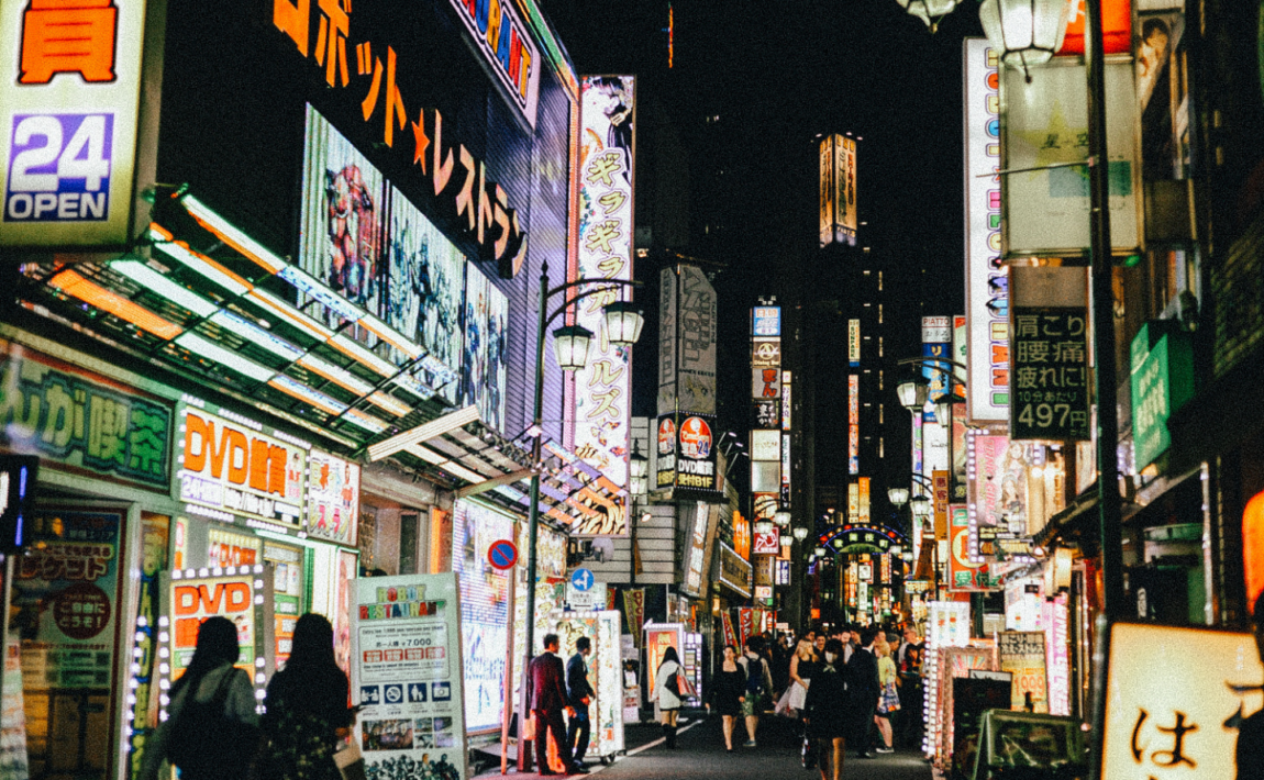 People walking down a street in tokyo at night.