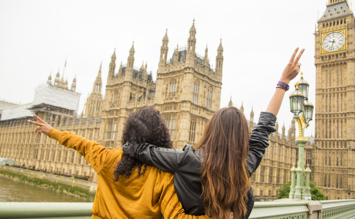 Two young women standing on a bridge overlooking Big Ben in Great Britain.