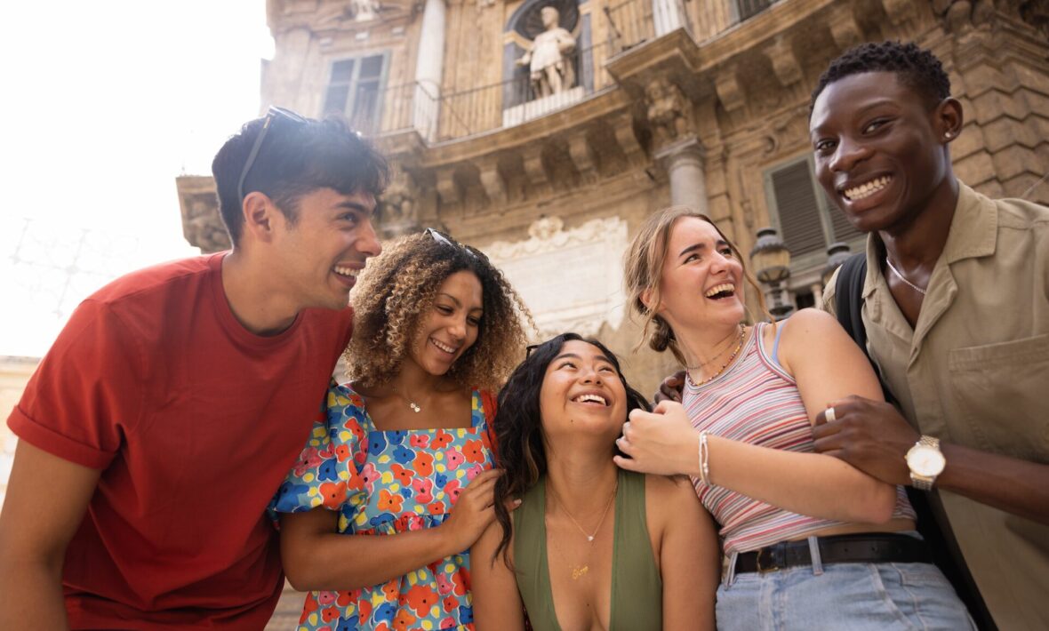 A group of young people laughing in front of one of the best places to visit in Italy.