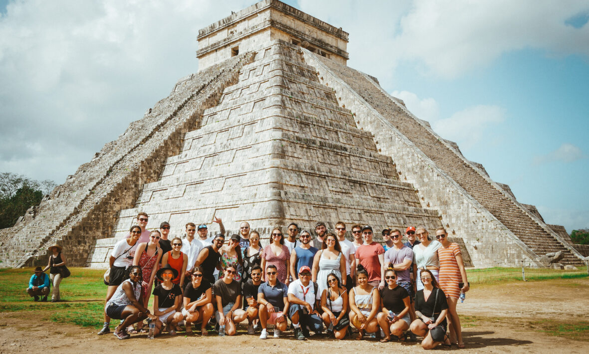 A group of sociable people posing in front of a pyramid.