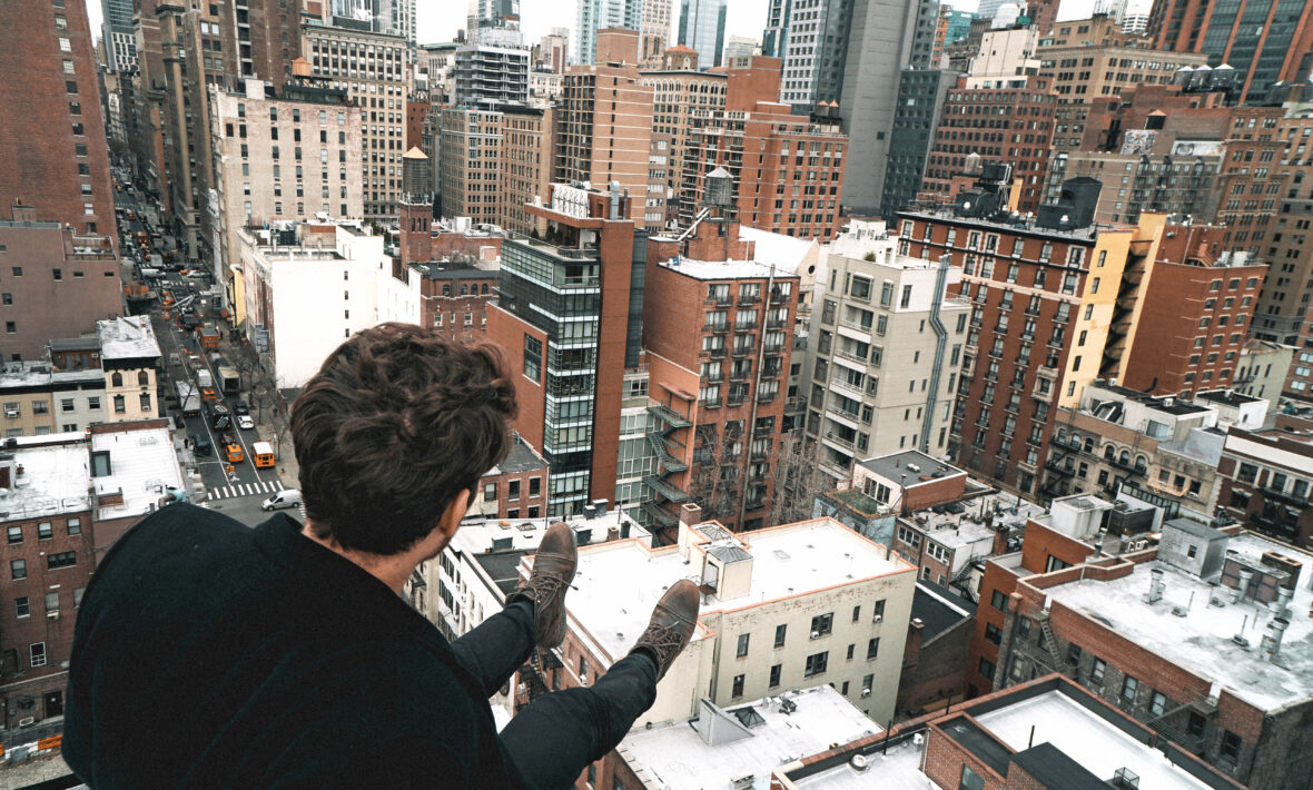 Sitting on edge of building surrounded by skyscrapers