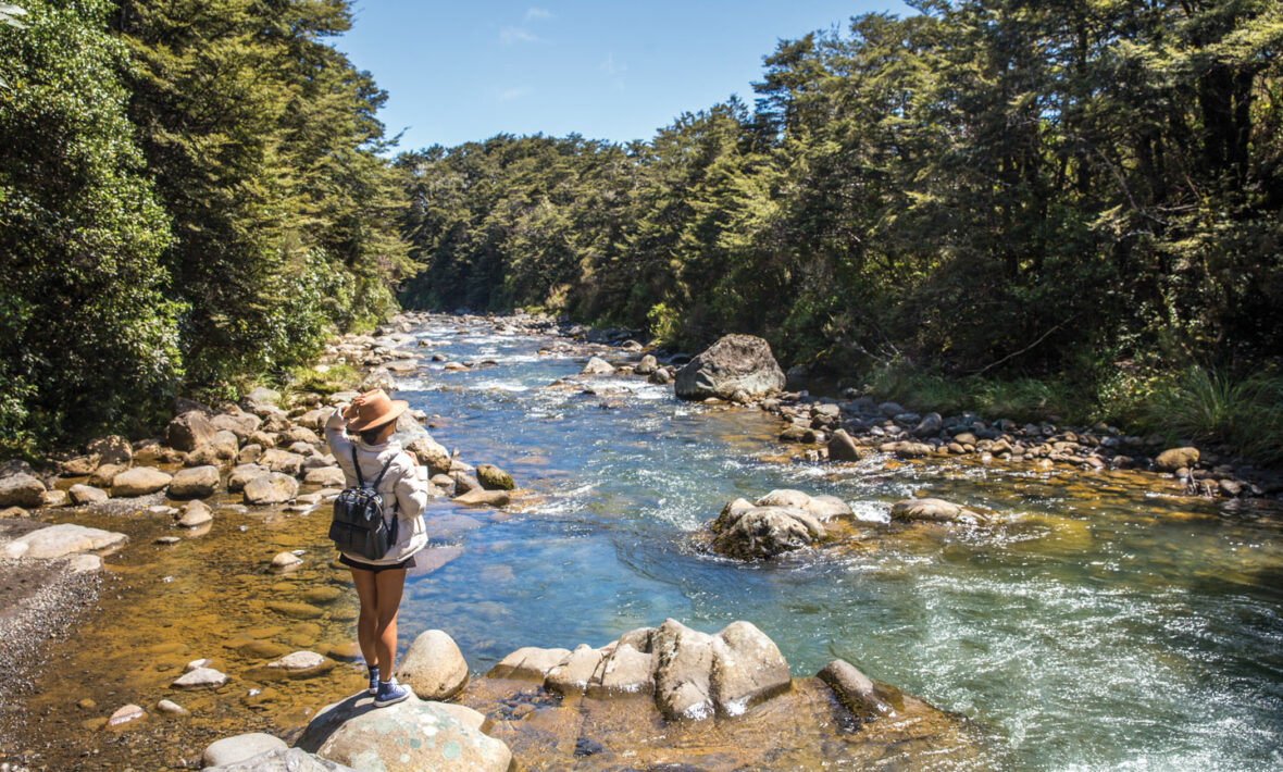 A woman enjoying outdoor activities near a river in New Zealand.